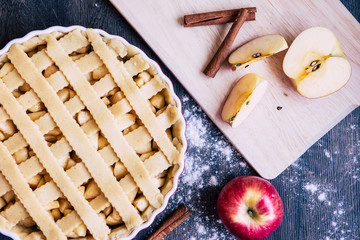 Traditional homemade apple pie and ingredients on wooden background for autumn holiday