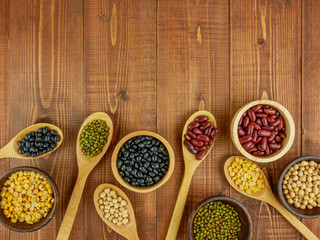 Flat lay,top view assorted beans including red bean,soybeans,black beans,mung beans on brown,beige wooden background with copy space