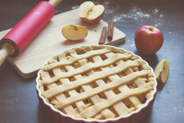 Traditional homemade apple pie and ingredients on wooden background for autumn holiday