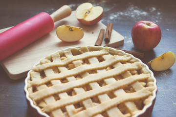 Traditional homemade apple pie and ingredients on wooden background for autumn holiday
