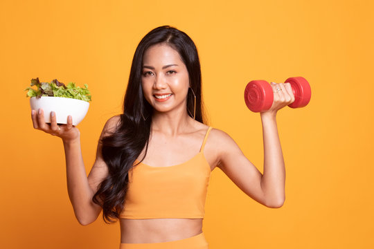 Healthy Asian woman with dumbbells and salad.