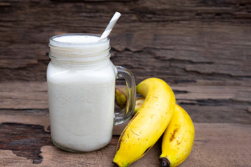 Banana fresh cocktail vanilla smoothies juice white fruit beverage healthy the taste yummy In glass for milkshake on wooden background from top view.