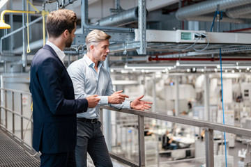 Two businessmen talking in a modern factory