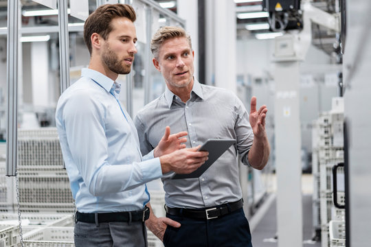 Two businessmen with tablet talking in a modern factory