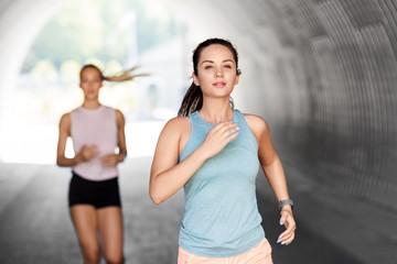fitness, sport and healthy lifestyle concept - young women or female friends running outdoors