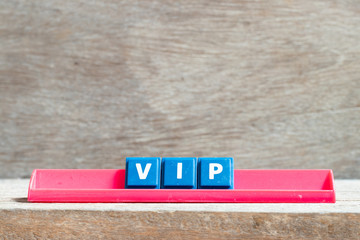 Tile letter on red rack in word VIP (abbreviation of very important person) on wood background