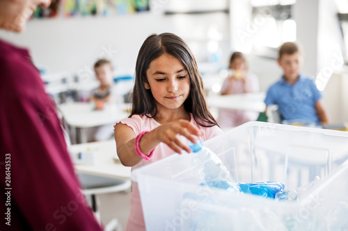 A teacher with small school kids in classroom learning about waste separation.