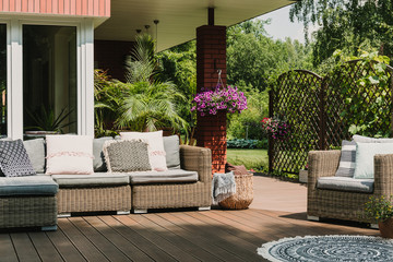Classy furniture on wooden terrace in green beautiful garden