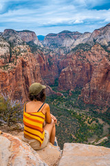 A young woman sitting enjoying the views of Zion from the Angels Landing Trail in Zion National Park, Utah. United States, vertical photography