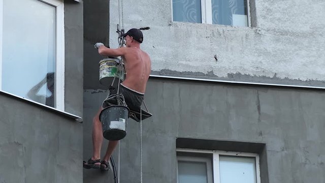 Builder working at height while holding on a rope and insurance