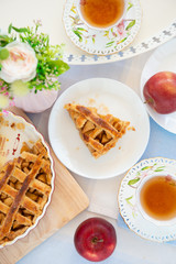 Fresh baked apple pie, cup of tea and flowers on a table