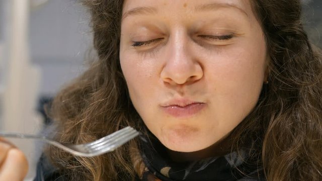 pretty girl eating a cake with a fork and chewing dessert closeup