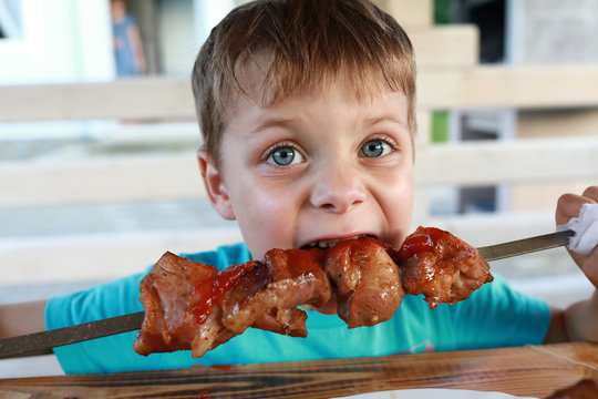 Boy eating pork neck kebab