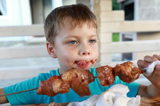Kid eating pork neck kebab