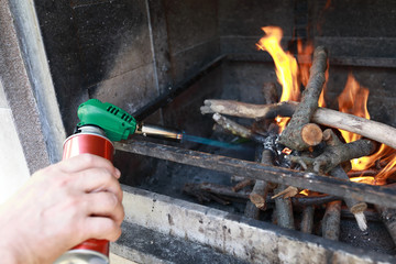 Person kindles firewood with gas burner