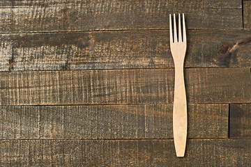 Single clean wooden fork lies on old brown rustic wooden planks. Space for text. Top view