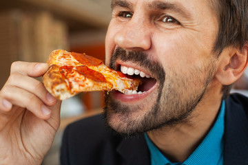 Bearded man eating pizza in a cafe