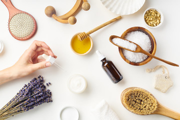 Fototapeta na wymiar Spa beauty skincare flatlay with lavender and fresh ingredients or homemade beauty products and scrubs. Female hand holding a jar of cream. Overhead view, copy space.