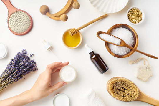 Spa beauty skincare flatlay with lavender and fresh ingredients or homemade beauty products and scrubs. Female hand holding a jar of cream. Overhead view, copy space.