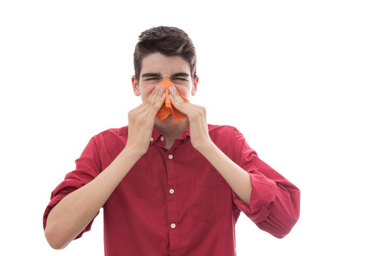 isolated young boy sneezing with handkerchief