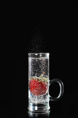 Strawberry berry in a glass narrow glass with sparkling water on a black background. Still life concept. Copy space.