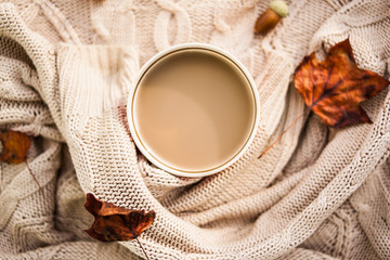 warm autumn. cup of coffee wrapped in a woolen beige sweater. still life.