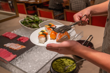 Man choosing delicious sushi in luxury buffet restaurant