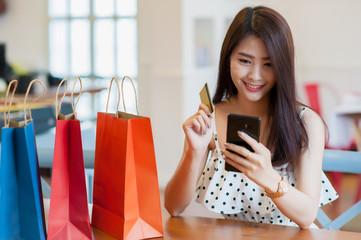 Asian girl shopping online happily.A multicolored paper bag placed next to it.