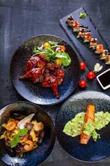 Top view on luxury restaurant food table with delicious meal. Flat lay food on dark background. Grilled meat, salmon, salads and suchi on table. Photo for menu, poster or banner