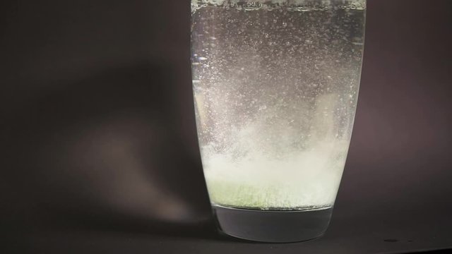Tablet form bath salt fall slowmotion in vase with decomposition reaction water