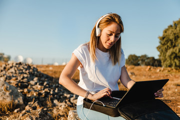 Young woman with her laptop communicates with antennas