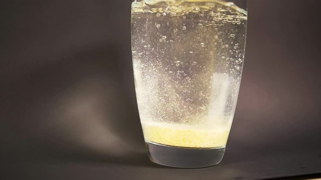 Bath salt form tablet drop slow motion in vase with decomposition reaction water