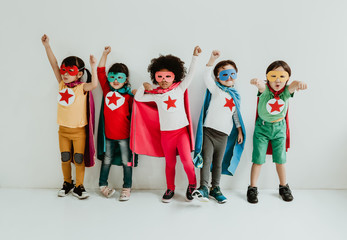 Group of Diverse Children Playing superhero on the white wall background. Superhero concept. Happy...