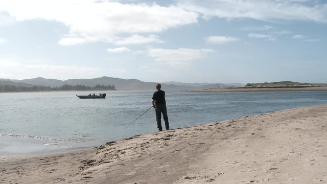 Man Fishing In Ocean Bay On Sunny Day