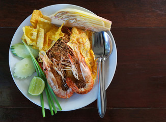 Thailand's national dishes with big shrimps and vegetables on wooden table, Asian rice noodles. Thai call 