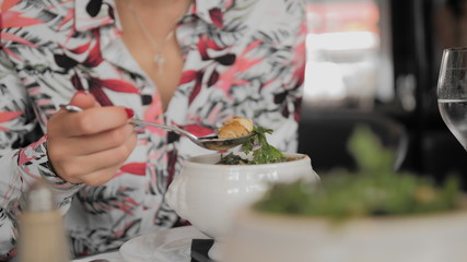 Unrecognized female tourist eats traditional soup with croutons, melted cheese and greens in a Paris restaurant. Hand takes a branch of dill. The concept of wrong etiquette. Close-up, Slow Motion.