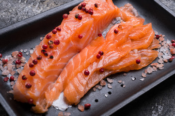 Raw fillet of salmon. Fresh salted and beautiful salmon fillet on black plate. Delicious fish meat. close up