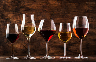 Wine set. Red, white and rose wine in assortment in wineglasses. Wine tasting, vintage wooden background, selective focus, copy space