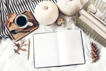 Autumn breakfast in bed composition. Blank open notepad, diary mockup. Cup of coffee, white pumpkins, plaid, oak leaves and old books. Linen background. Thanksgiving, Halloween. Flat lay. Top view.