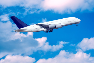 Fototapeta na wymiar Big jet taking off in blue cloudy sky.