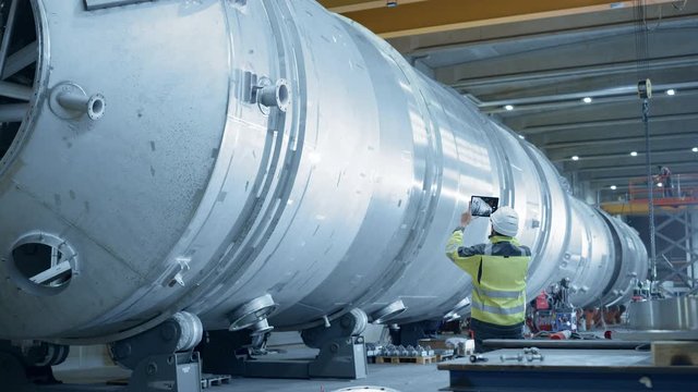 Heavy Industry Engineer Uses Augmented Reality Digital Tablet to Scan Large Diameter Pipe. Modern Industrial Manufacturing Technology to Design and Construct Oil, Gas and Fuels Transport Pipeline.