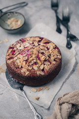 Rhubarb strawberry cake with almond slices on grey surface