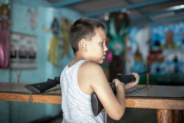 teen boy holding a rifle in the dash at the shooting range aiming at the goal and playing in the Park