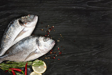 Fresh fish dorado. Dorado and ingredients for cooking on a black table.