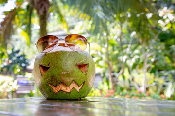 Fresh green coconut in a shape of halloween pumpkin. coconut with a face carved on it is on the table