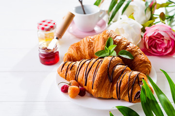 Breakfast on white wooden background - croissant, jam, berries and coffee