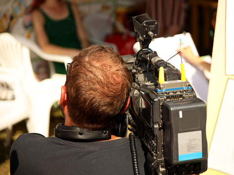 The operator shoots a report for television on a professional video camera. Release of news to the public. High-tech video equipment for the production of high-quality content. Rear view of the camera