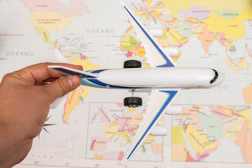 Woman hand holding a toy airplane with a map as background
