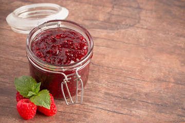 Jar of Raspberry Jam on a Rustic Wooden Table