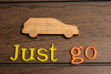 Wooden little car and the phrase let go made from colorful letters on a wooden background